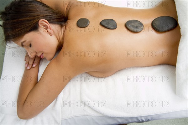 Hispanic woman having hot stone therapy