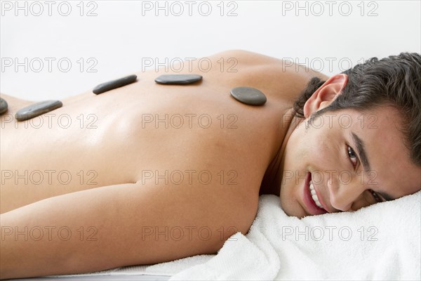 Hispanic man having hot stone therapy