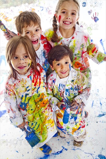 Messy Hispanic children covered in paint