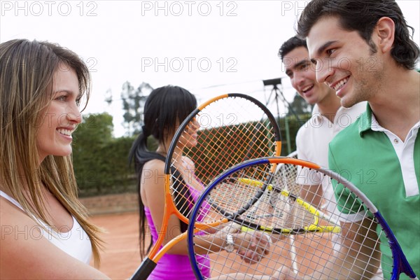 Hispanic friends playing double's tennis