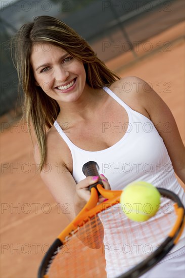 Hispanic woman balancing tennis ball on racquet