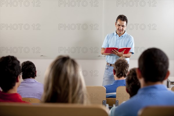 Hispanic college students listening to teacher in classroom