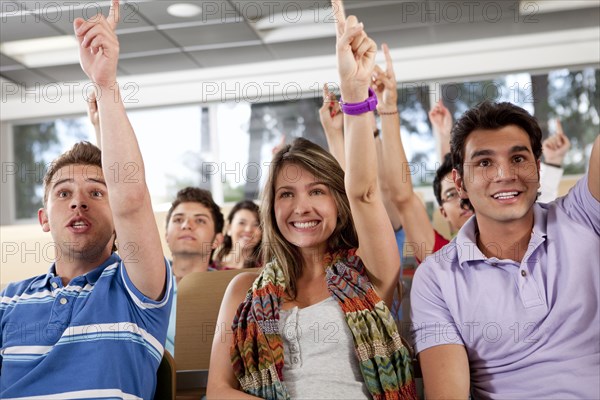 Hispanic college students raising arms in classroom