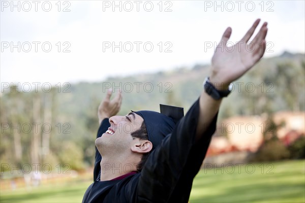 Hispanic college graduate cheering with arms raised