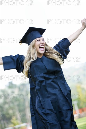 Hispanic college graduate cheering with arms raised