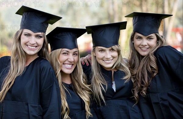 Hispanic college graduates standing together in caps and gowns