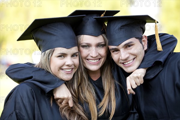 Hispanic graduates in caps and gowns hugging