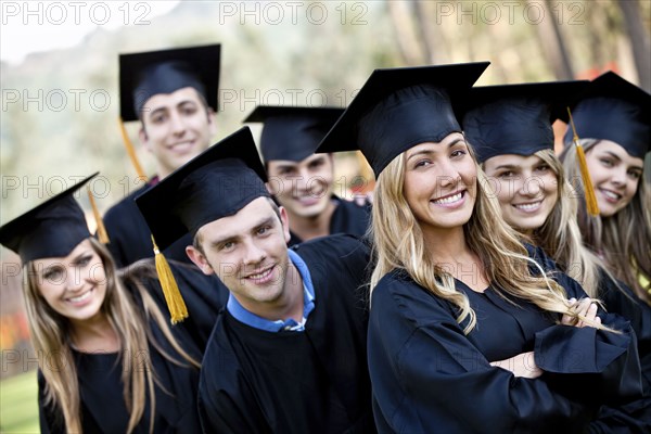 Hispanic graduates in caps and gowns standing together