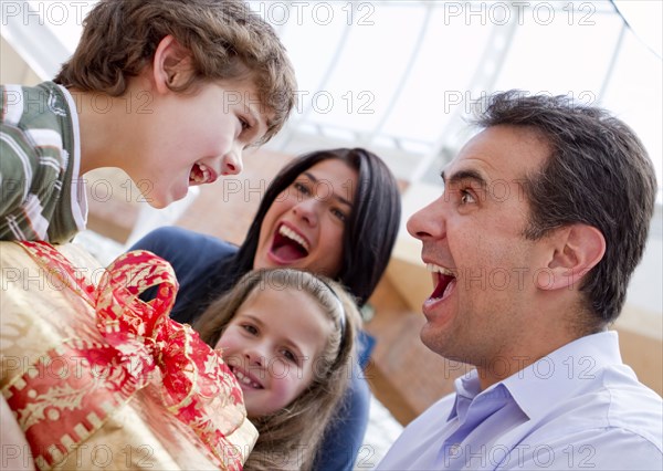 Hispanic father giving excited son birthday gift