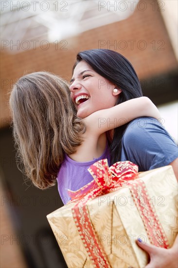 Hispanic girl giving happy mother birthday gift