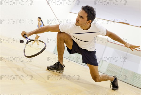 Hispanic couple playing squash