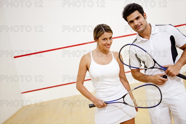 Hispanic couple holding squash racquets