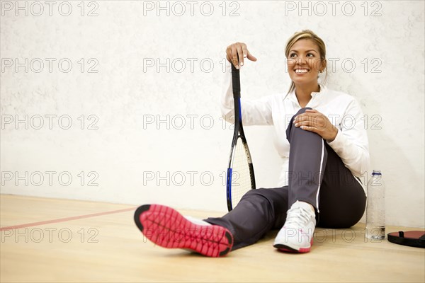 Hispanic woman relaxing on squash court