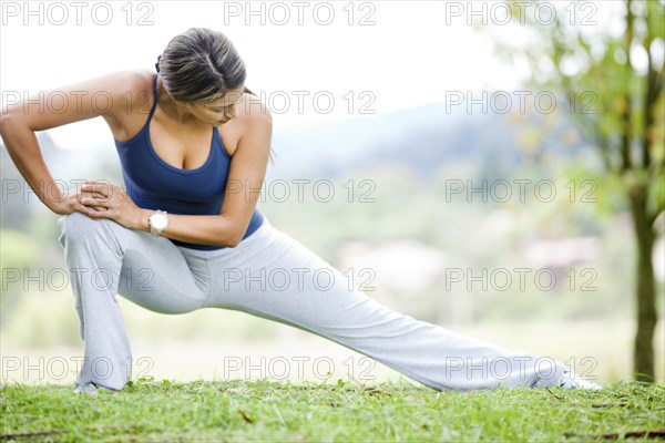 Hispanic woman stretching in grass