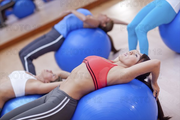 Hispanic women using exercise balls in gym