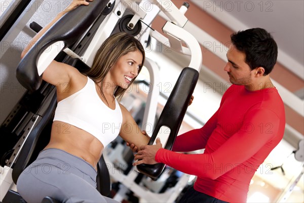 Hispanic woman working with trainer in gym