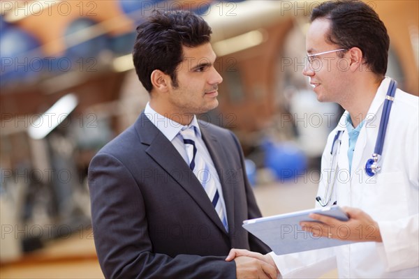 Hispanic doctor and businessman shaking hands