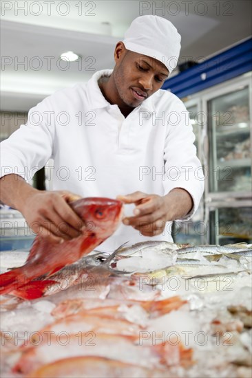 Mixed race grocer preparing fish in market