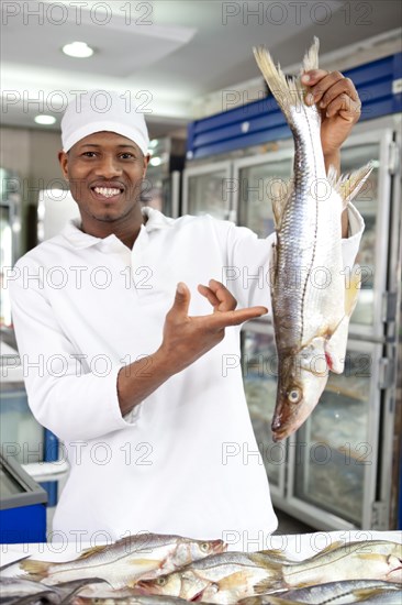 Mixed race grocer preparing fish in market