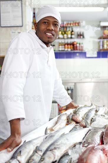 Mixed race grocer preparing fish in market