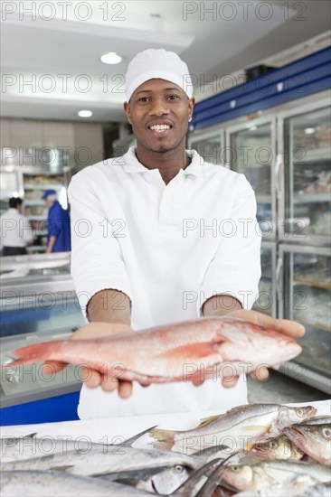 Mixed race grocer preparing fish in market