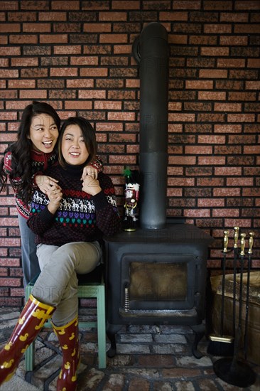 Chinese mother and daughter hugging near fireplace