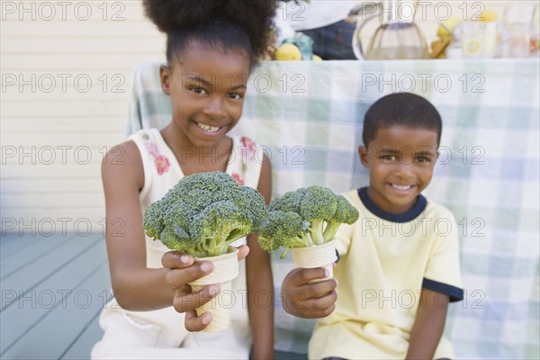 Mixed race children holding broccoli cones