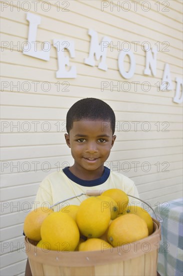 Mixed race boy holding basket of lemons