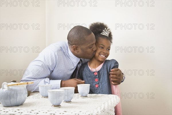 African father kissing daughter with tiara