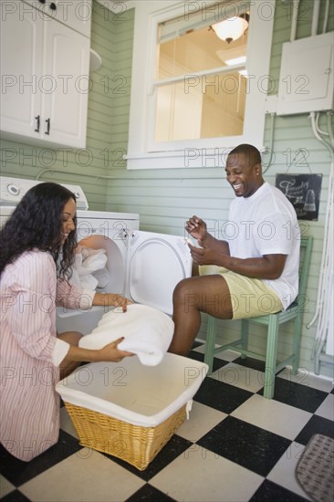 African husband helping wife fold laundry