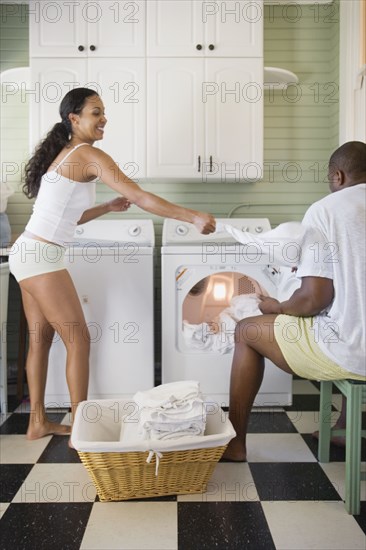 Playful couple folding laundry