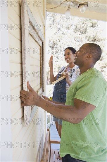 Couple attaching frame to outside of house