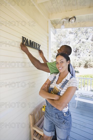 Couple hanging family sign on house