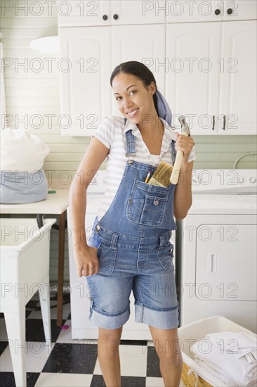 Mixed race woman holding hammer in laundry room