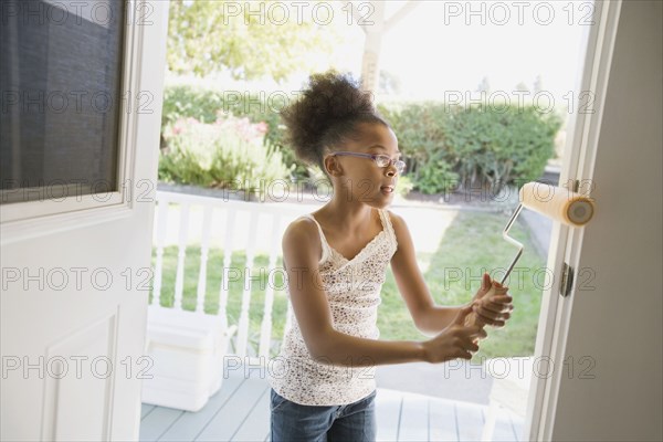 Mixed race girl painting doorway