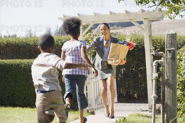 Children running to mother carry groceries