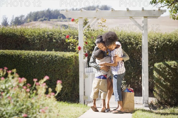 Mother with groceries hugging children