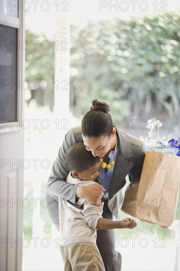 Mother with groceries hugging son