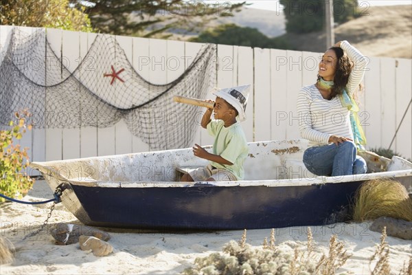 Mixed race mother and son pretending to sail in a boat