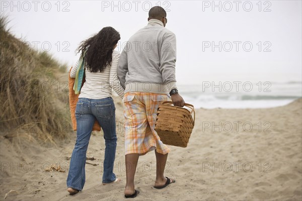 Couple walking on beach with picnic basket