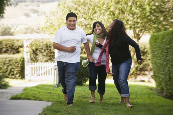 Hispanic siblings running on grass