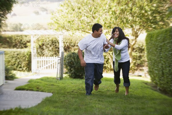 Hispanic brother and sister running on grass