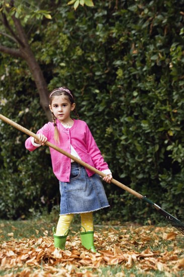 Middle Eastern girl raking leaves