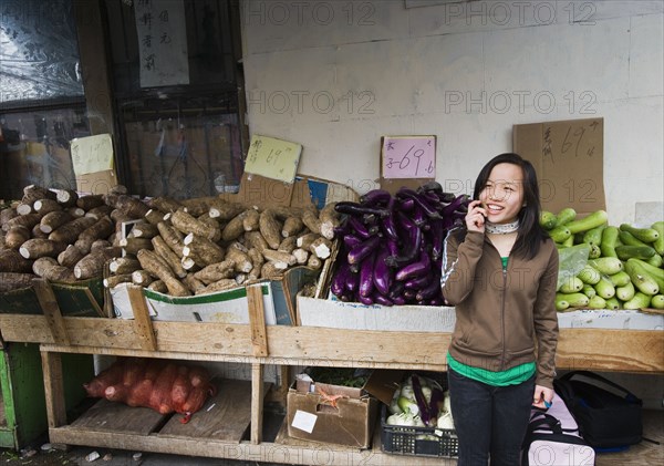 Chinese girl talking on cell phone at outdoor market