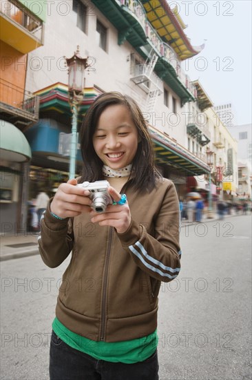 Chinese girl holding digital camera on urban street