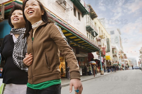 Chinese mother and daughter walking down urban street