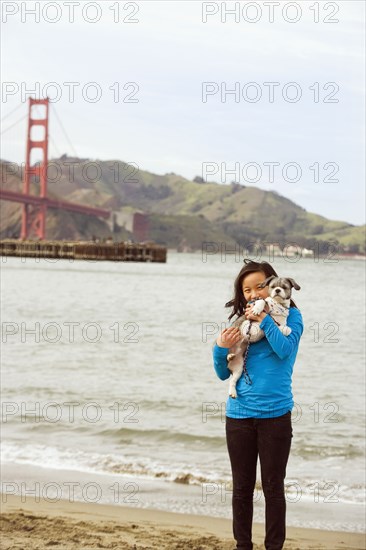 Chinese girl holding dog on beach