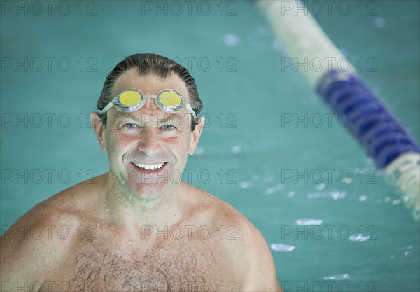 Smiling man with goggles in swimming pool