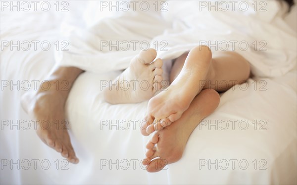 Close up of couple's feet in bed