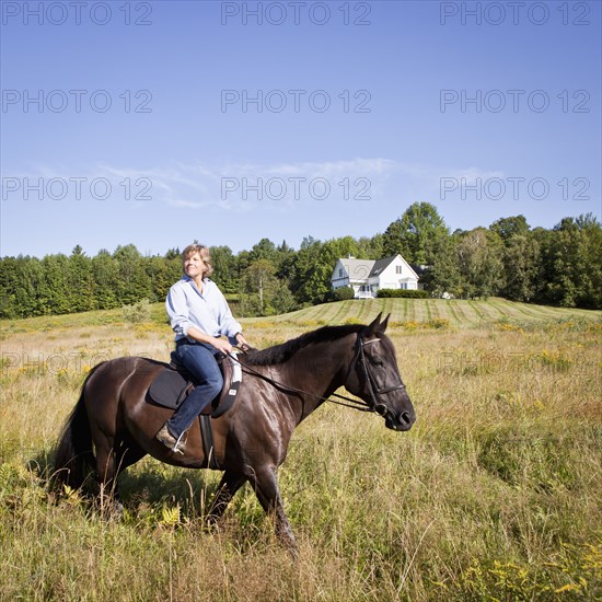 Caucasian woman riding horse in field